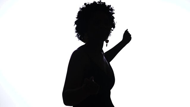 Silhouette of woman with curly hair dancing Puerto Rican bomba on white background in 60fps