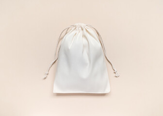 eco-friendly white cotton bag with ties on peach background