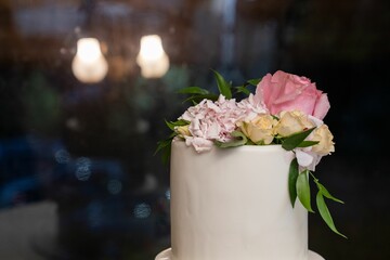 Closeup shot of a white wedding cake adorned with pink floral decorations.