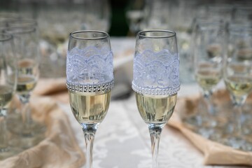 Closeup of two champagne flutes with decorative laces on the wedding table.