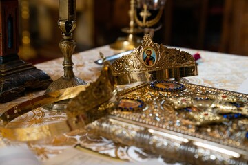 Intricately detailed gold crown on a pristine white tablecloth in an Orthodox church.