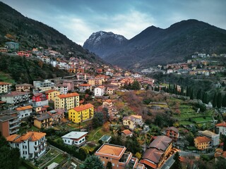 Naklejka na ściany i meble Drone view of Lake Como surrounded by a town and mountains in the evening in Italy