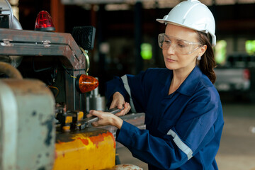 Female mechanical engineer working in machinery in industry. Workers wearing safety glasses....