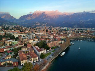 Fototapeta na wymiar Drone view of Lake Como surrounded by a town and mountains in the evening in Italy