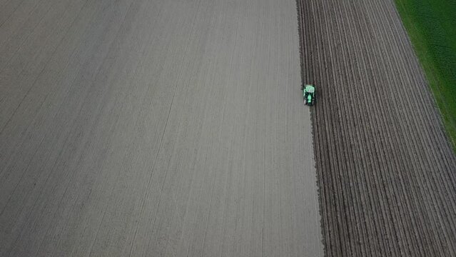 Un agriculteur s&egrave;me des pommes de  terre dans un champ avec son trateur