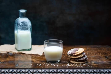 Fotobehang Closeup shot of a glass of milk and cookies on the table © Francisco Gomez PerpiÑan/Wirestock Creators