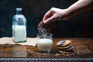 Fotobehang Closeup shot of a person putting the cookie in a glass of milk © Francisco Gomez PerpiÑan/Wirestock Creators