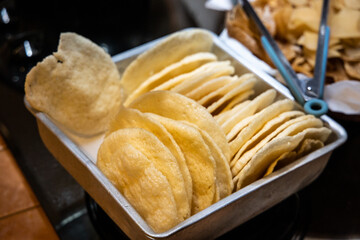Freshly fried prawn crackers are arranged neatly in tray.