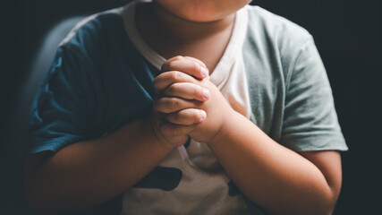 Little boy praying to God with hands held together. Child worship to God. Cute little boy in a...