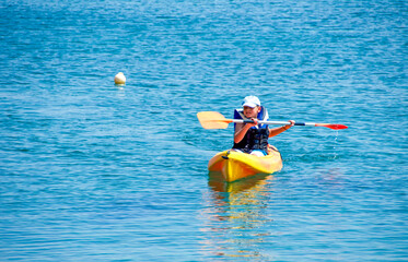 kayaking lessons. Boy with  life buoy suit in kayak lessons during summer vacations in an island of Greece.