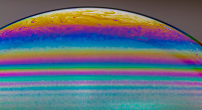 Vivid rainbow colours of a Macro soap bubbles creating psychedelic patterns under light dome © Elias Bitar
