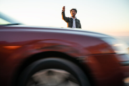 Black man with skateboard hitchhiking on road