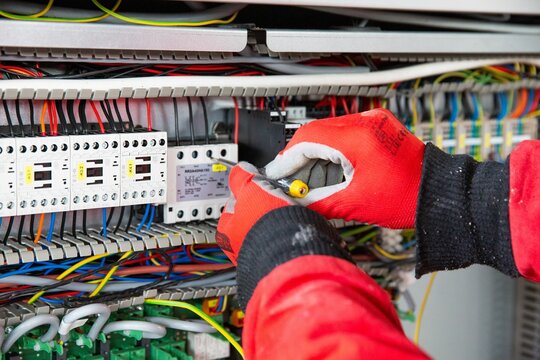 Closeup of hands in gloves doing electrical installation work.