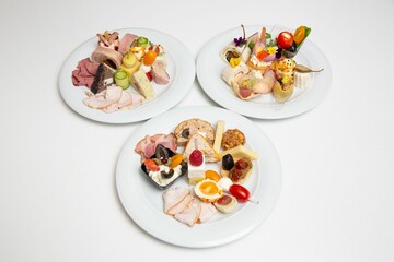 Closeup of plates with different types of cheese and ham.