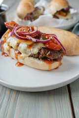 Cheeseburger on french baguette bun with tomatoes, pickles, red onions and homemade barbecue sauce.