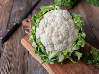 Whole cauliflower head with leaves isolated on wooden table with copy space
