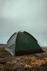 Vertical shot of a green tent on a highland covered in clouds © Hamza Oulad/Wirestock Creators