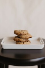 Vertical shot of freshly-baked chocolate cookies on a ceramic tray on the table