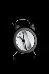 Small alarm clock on a black background.