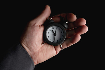 Alarm clock in hand on a black background.