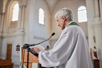 Senior priest reading sermon in microphone standing behind the altar at ceremony in church