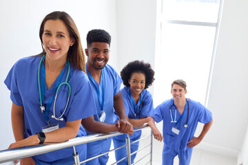 Portrait Of Multi Cultural Medical Team Wearing Scrubs Standing On Stairs In Hospital 