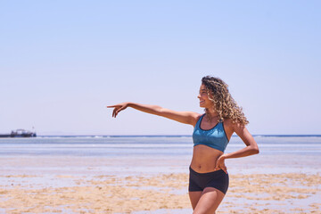 Portrait of young beautiful Brazilian girl staying on warm sunny beach and laughing.Latin woman with long curly hair enjoying her summer vacation on a sunny day.    