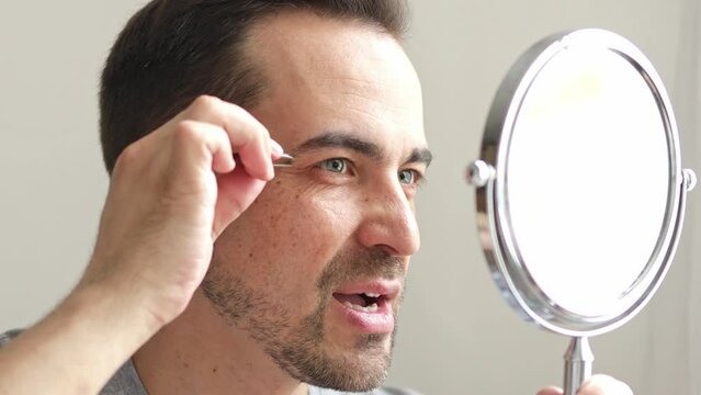 a man plucks hairs from his eyebrows. the concept of male self-care. metrosexual.