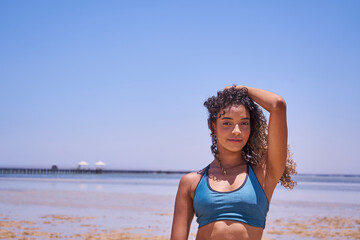 Portrait of young beautiful Brazilian girl staying on warm sunny beach and laughing.Latin woman with long curly hair enjoying her summer vacation on a sunny day.    