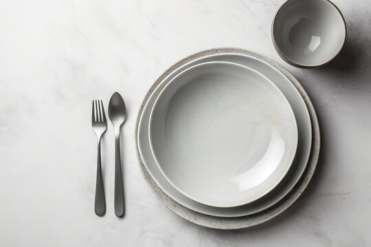  a white plate with a fork and a bowl with a spoon and a spoon rest on a marble surface with a white marble table top.  generative ai