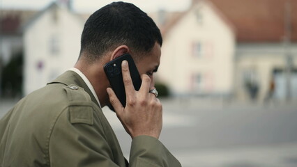 Closeup of person speaking on phone outside in city street. Tracking shot in motion of man holding...