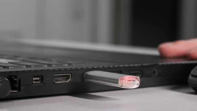 female hand inserts USB flash drive into laptop to transfer information, close-up