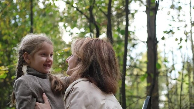 Hello September. A young mother and little daughter walk in the city park in autumn.