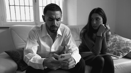 Boyfriend addicted to technology while ignoring girlfriend sitting on couch at home. People...