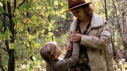 Hello September. A young mother and little daughter walk in the city park in autumn.