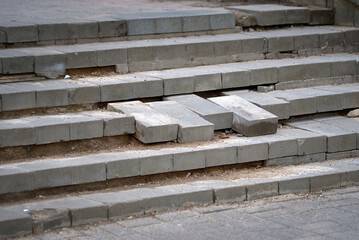 Damaged stair steps made from paving slab unsafe for pedestrians. Broken staircase. Broken stair with steps from gray paving slabs. Poor quality of brickwork. Renovation and repair work concept.