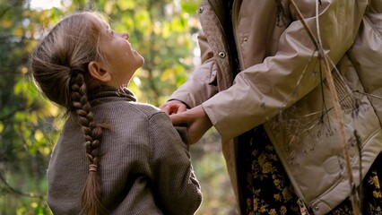 Hello September. A young mother and little daughter walk in the city park in autumn.