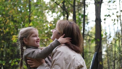 Hello September. A young mother and little daughter walk in the city park in autumn.