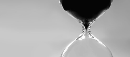 Sand moves through hourglass. Close up of hour glass clock. Hourglass as time passing concept for business deadline, urgency and running out of time. Black and white image. Copy space.