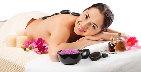 Beautiful young woman receiving hot stone massage at salon spa