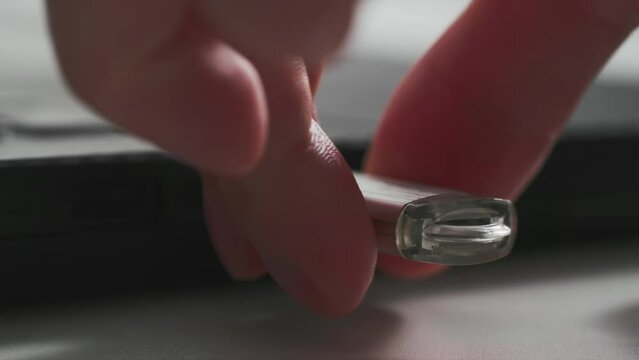 young woman turns on a portable USB flash drive with a work indicator in laptop for data transfer, blueprint