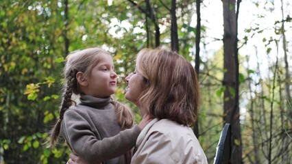 Hello September. A young mother and little daughter walk in the city park in autumn.