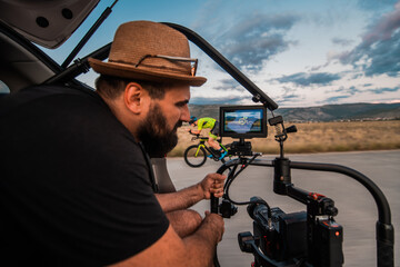 A videographer recording a triathlete riding his bike preparing for an upcoming marathon.Athlete's...