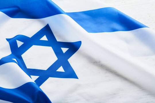Independence Day of Israel. National Israel flag with star of David over white wooden background. Close up. National flag with place for text.