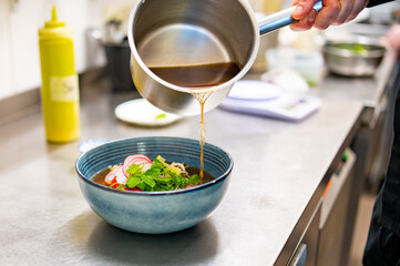 Close up of chef's hands cooking asian pho bo soup on restaurant kitchen