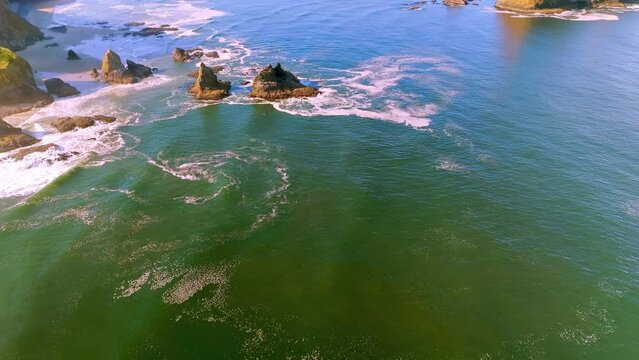 Experience the ocean's beauty as the camera gently flies above, tilting up and moving back to show the amazing sea stacks and sunlit Three Arch Rocks. Enjoy the bright greens and blues of the water.