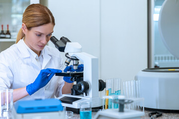 Female scientist looking petri dish with genetically modified sample chemicals under microscope