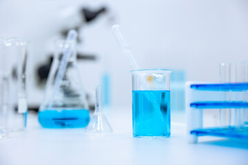 Laboratory glassware with color liquid and microscope, microbiologist or chemist place of work.