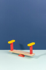 Wooden seesaw in equilibrium still life concept balance on dark blue and light blue background....