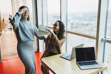 A pregnant woman is working in the office with a colleague on a new project, they are looking at a...